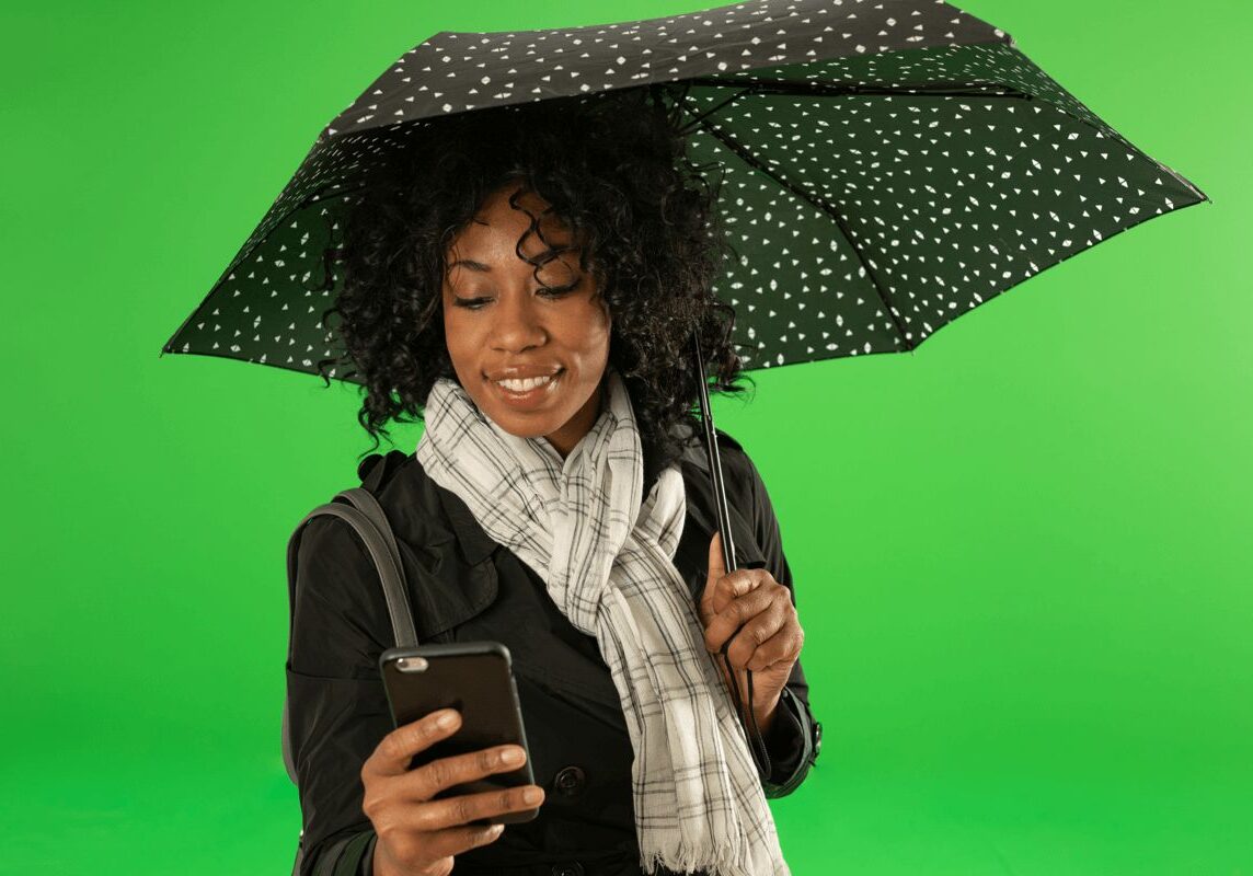 woman under umbrella looking at phone