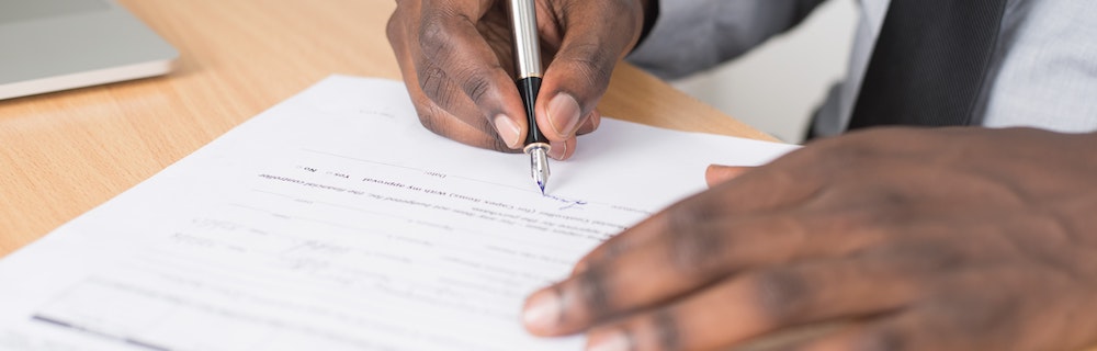 A man signs official paperwork.